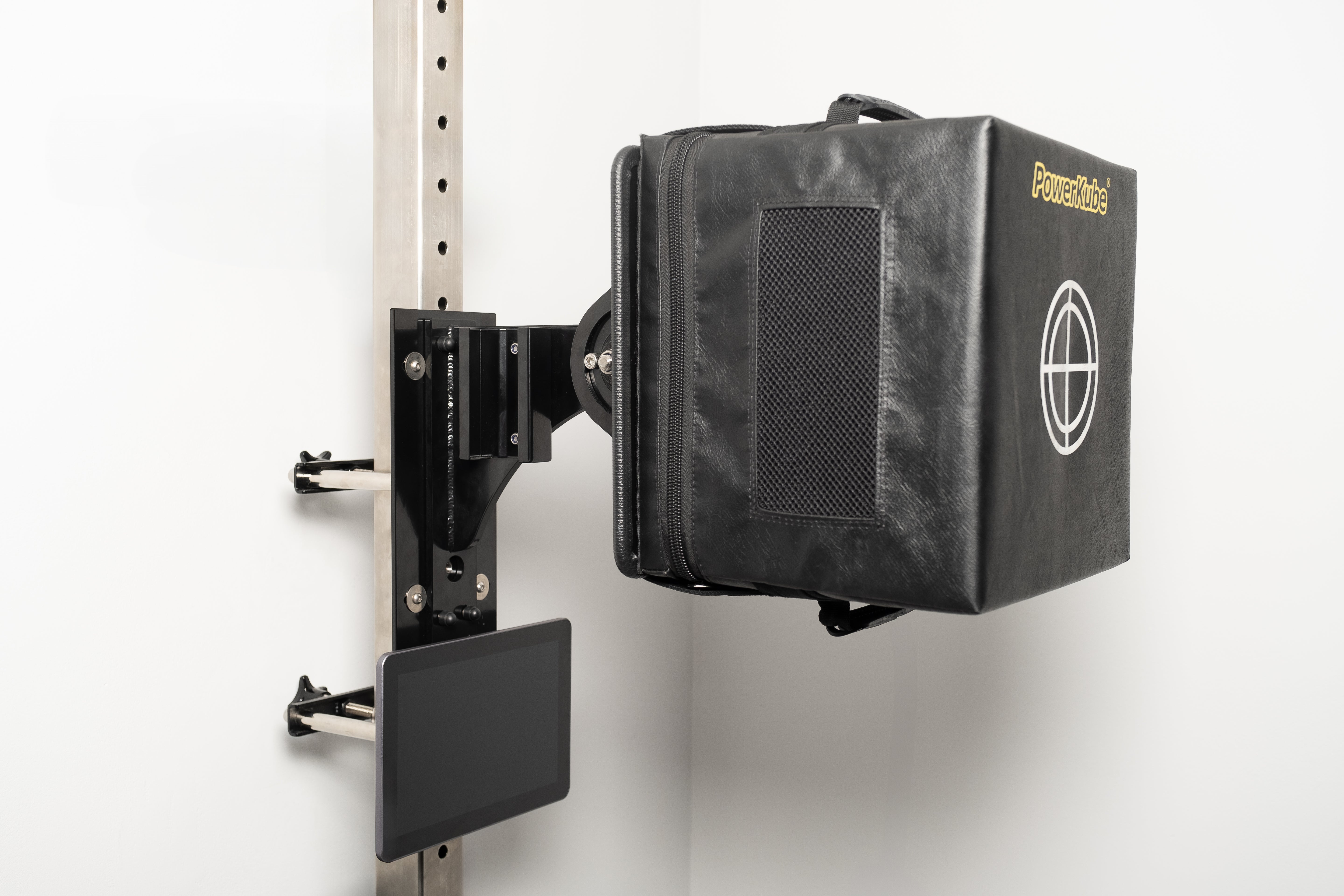 A black PowerKube Rig Mount attached to a white wall, designed to measure striking power, reaction time, and endurance.