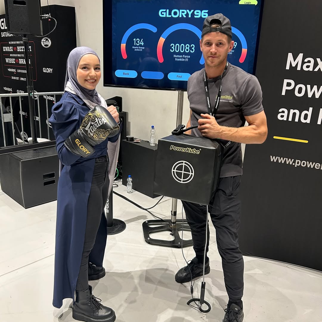 A woman stands next to the PowerKube Go smart punching bag